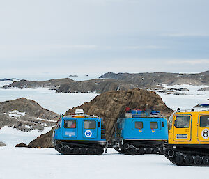Blue and yellow hagglund on the plateau. Sea ice and islands below