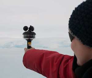 Expeditioner holding an instrument which reads the wind speed and direction