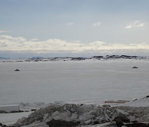 Two snow groomers driving towards each other on the sea ice