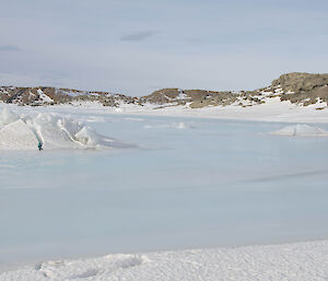 Still water on top of sea ice land in the background