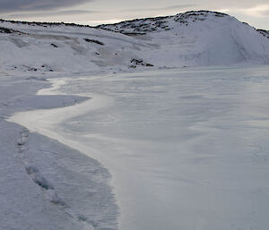 Footprints in the snow along the edge of the flooded fjord