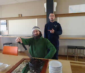 Rob cutting a chocolate cake while Stu looks on