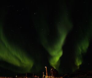 Bright green aurora australis above station buildings