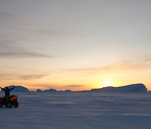Quad bike rider with icebergs and a sunset in the background
