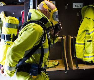 Expeditioner wearing firefighting gear places mask over face