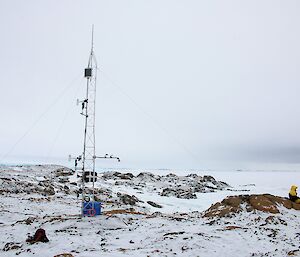 Expeditioner sitting on a rocky hill looking out towards open water