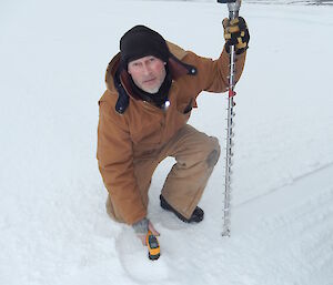 Expeditioner placing a temperature gauge in the sea ice