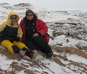 Two expeditioners sitting on snow covered rock