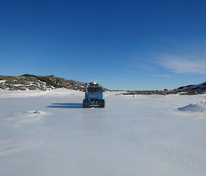 Blue Hägglunds driving on smooth milky sea ice