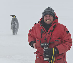 Expeditioner with an emperor penguin in the background