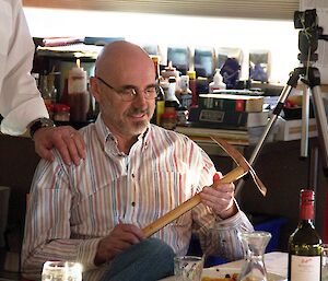 Expeditioner holding a handmade ice axe at the dinner table