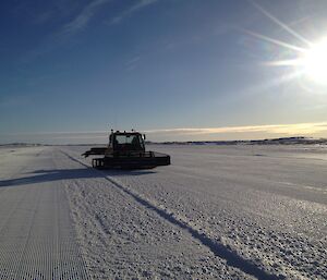 Large groomer driving in a straign line on a groomed flat area of sea ice