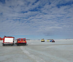 Red hagglund on the sea ice with a yellow Hägglunds in the background