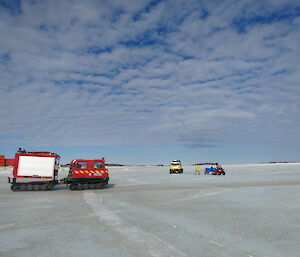 Red hagglund on the sea ice with a yellow Hägglunds in the background