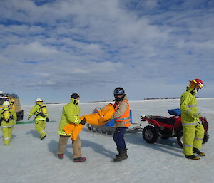 Two expeditioners carrying a mannequin to safety
