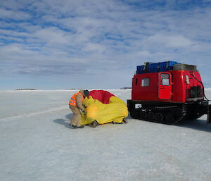 Expeditioners under a bright yellow and red bivy