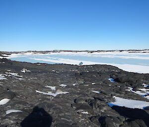 Looking down over the sea ice, island covered in black rock