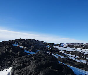 Expeditioner on top of a hill, black rock