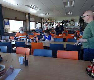 A number of people spread out over rows of tables