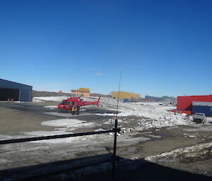 Expeditioner dressed in yellow jacket stepping out of a red helicopter