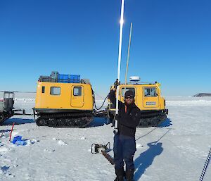 Expeditioner holding a long metal pole ready to place it through the hole in the sea ice
