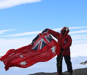 Expeditioner holding up an old Australian flag