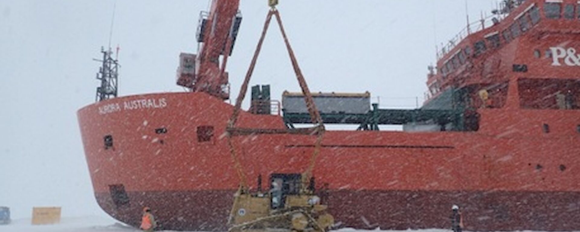 A bulldozer is loaded from the ice onto large icebreaker ship Aurora Australis for return to Australia