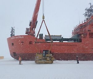 A bulldozer is loaded from the ice onto large icebreaker ship Aurora Australis for return to Australia