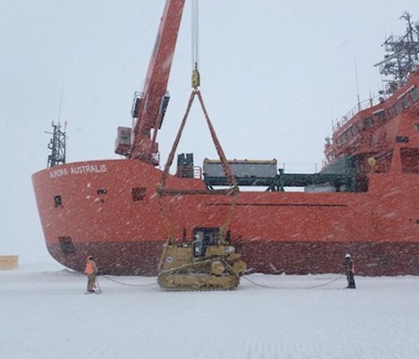 A bulldozer is loaded from the ice onto large icebreaker ship Aurora Australis for return to Australia