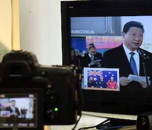 Videocamera filming video screen with expeditioners and Chinese president