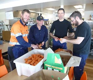 Four helicopter team members peeling vegetables in the kitchen during a no flying period