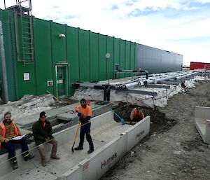 Four tradespersons sitting on a concrete culvert facing the camera