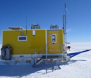 a yellow pre-fabricated towable hut on the plateau. Aeroplane in background