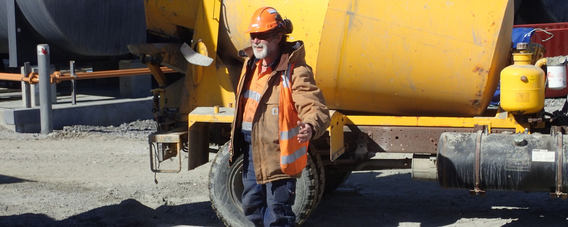 Tradesperson standing in front of a cement truck looking at the camera