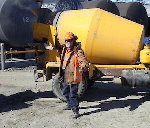 Tradesperson standing in front of a cement truck looking at the camera