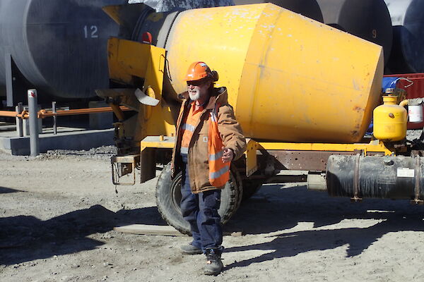 Tradesperson standing in front of a cement truck looking at the camera