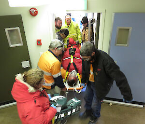 A fake injured man is carried through a doorway on a stretcher as part of a training exercise