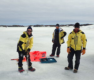 Expeditioners drilling into the sea ice to gain ice thickness measurement