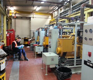 Tradesperson sitting on a chair facing a control panel