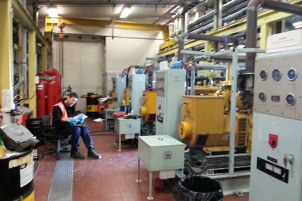 Tradesperson sitting on a chair facing a control panel