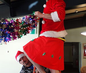 Two expeditioners hanging christmas decorations whilst standing on a ladder