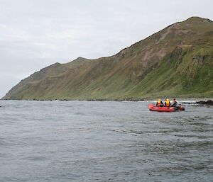 Long shot of orange boat on water with land in background