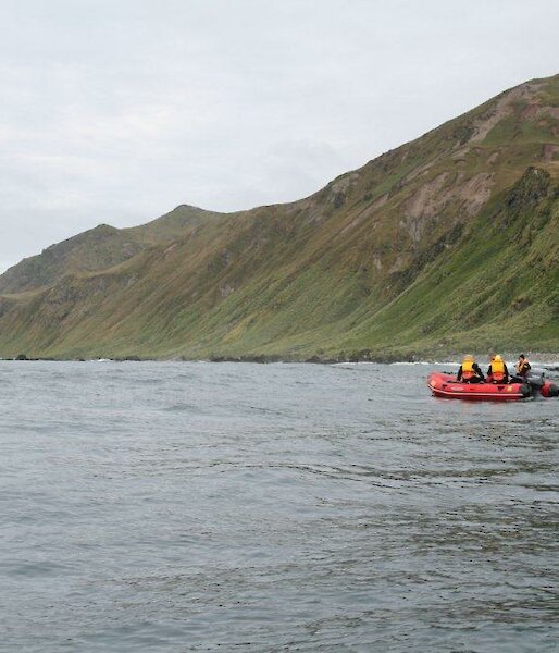 Long shot of orange boat on water with land in background