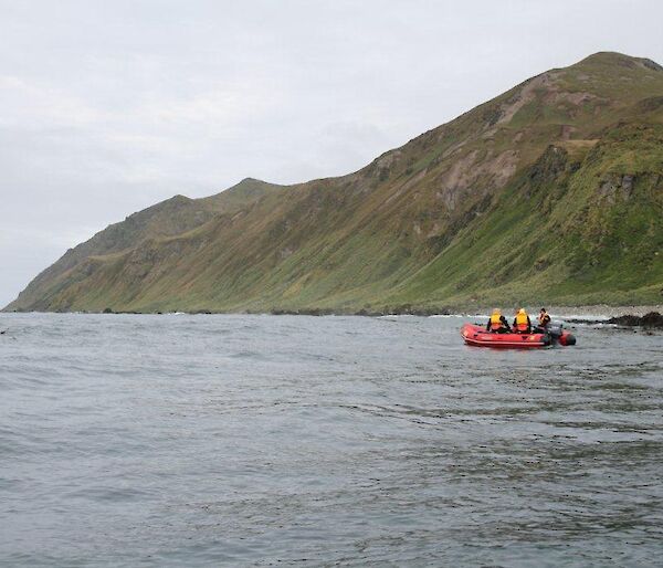 Long shot of orange boat on water with land in background