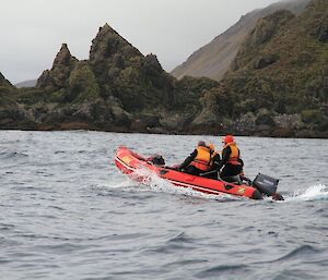 Expeditioners in a rubber boat with grassy hills in the background