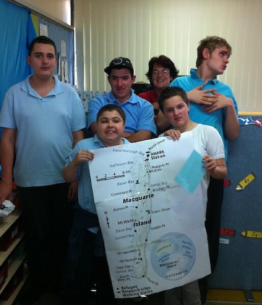 Five school students and their teacher hold a map of Macquarie Island.