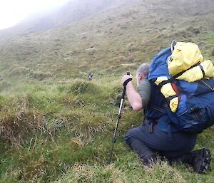 Expeditioner hunkers down in grass to try and spot a possible rabbit.