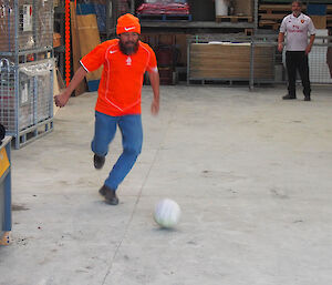Expeditioner kicking soccer ball inside shed