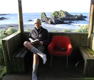 Stu relaxing on his day off reading a book with beach in background