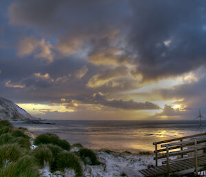 Sunrise at Brothers Point with ocean framed by land and cloud cover trying to choke out the emerging sunshine